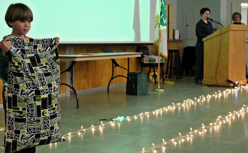 Ezra Foster shows off his sewing creation at a recent 4-H fashion show in Gray. Speaking at the podium is Sarah Sparks, with 4-H leader Leslie McDonnell at far right.