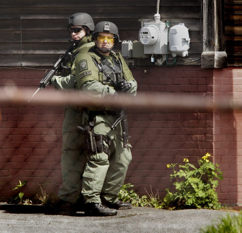Heavily armed members of Portland Police’s Special Reaction Team position themselves on Cedar Street while trying to apprehend shooting suspect Brian Kelley in Portland on Saturday.