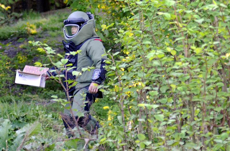 BOMB SEARCH: Maine State Police Sgt. Jeff Mills carries material to detonate Thursday outside an apartment building on Gage Street in Augusta. Law enforcement officers from several agencies searched two apartment buildings on the street for explosive materials. The State Police Bombs Team exploded material located in an apartment on Gage Street in the yard behind behind it.