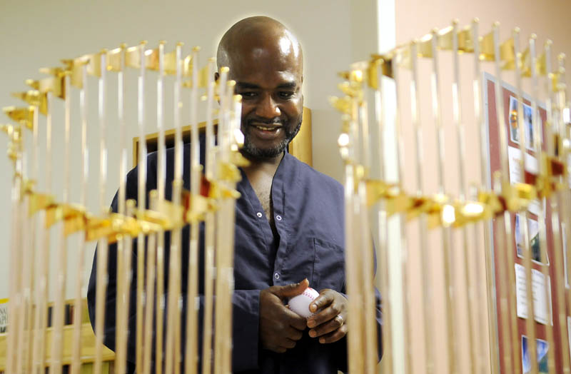 Clutching a baseball he received from the Fenway Ambassadors, VA Maine Healthcare System-Togus patient Robert Johnson Jr., of Searsport, inspects the Red Sox World Series trophies on display Wednesday at the hospital for veterans.