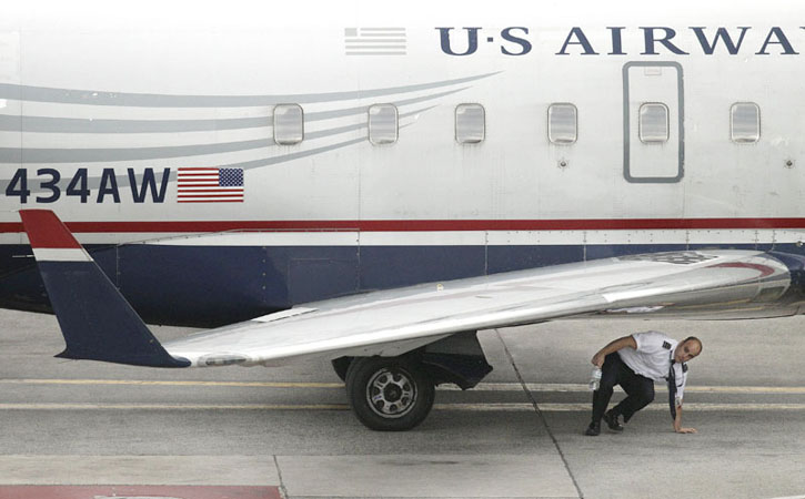 A member of the flight crew on U.S. Airways commuter jet, tail number N434AW, completes a walk-around of the aircraft at Logan International Airport in Boston on Thursday.