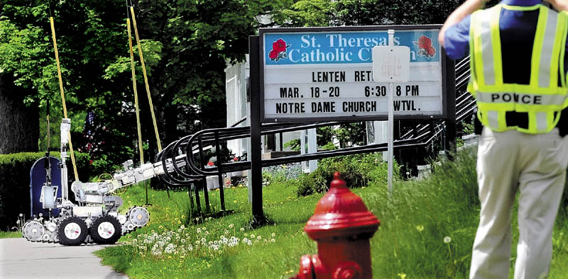 A Maine state Police remote-controlled robot approaches the steps in front of St. Theresa's Catholic Church in Oakalnd on Wednesday after a suspicious object believed to be a pipe bomb was discovered. The robot detonated the object, and it turned out it was not an explosive device.