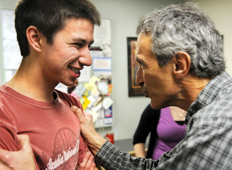 Jared Diou-Cass gets a hearty congratulations from his physics teacher, Steve DeAngelis, right, at Maranacook Community High School after receiving a $100,000 scholarship Monday. Diou-Cass plans to attend Union College in Schenectady, N.Y., where yearly costs are more than $56,000.