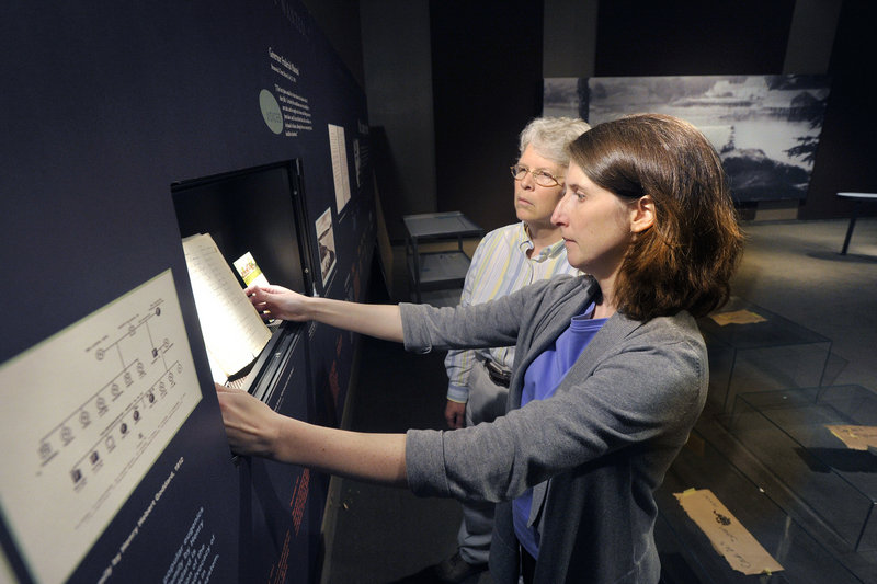 Kate McBrien, front, and Linda Carrell evaluate the placement of a cemetery burial book from the Maine School for the Feebleminded, circa 1915.