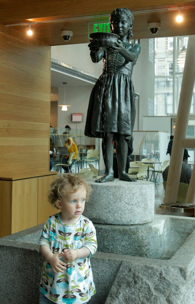 Fifteen-month-old Aliyah Goss looks out a window of the Portland Public Library near "The Little Water Girl" on Thursday.