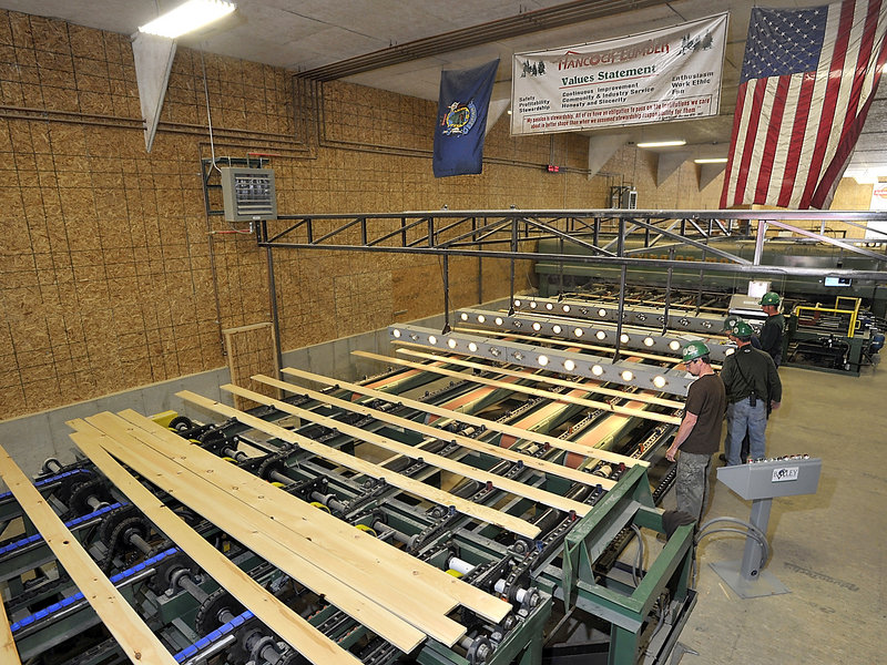 Workers guide planed boards that are going to a machine that will cut them to exact lengths at Hancock Lumber in Casco. Customized orders are a specialty of Hancock.