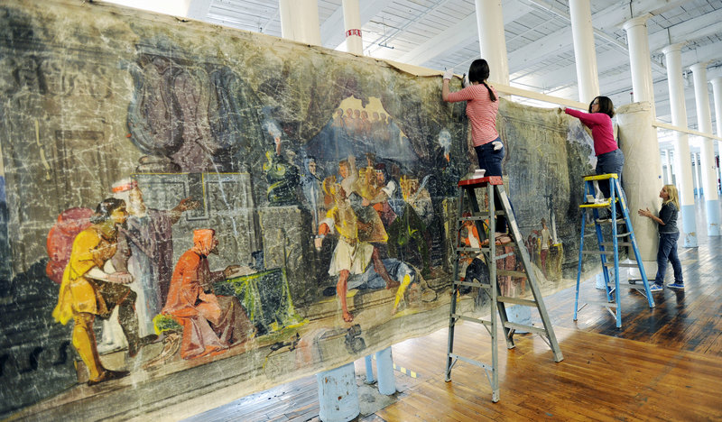 Anna Kelley, left, Saco Museum director Jessica Skwire Routhier and Marie O’Brien hang the scroll, which was created in 1851 and based on the 1678 book by John Bunyan, “The Pilgrim’s Progress.”