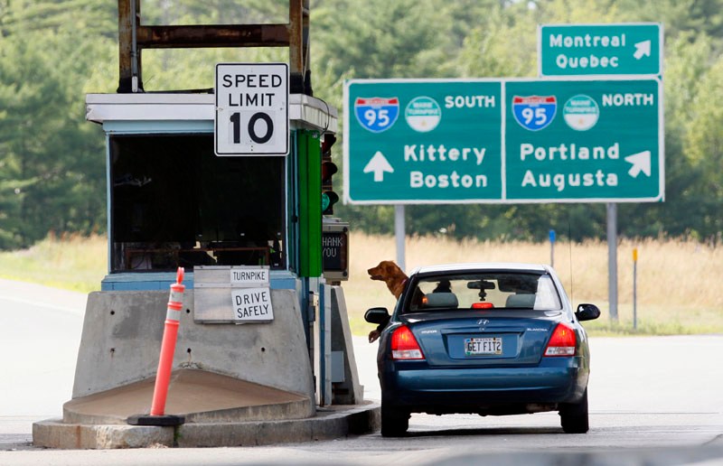 A motorist and her dog wait for change at a toll booth, Thursday, July 19, 2012, in Biddeford. The Maine Turnpike Authority may scale back its proposed toll increase. (AP Photo/Robert F. Bukaty)