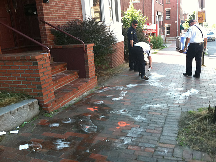 Portland Fire Department personnel clean up at the scene of a shooting on India Street this morning that left blood splattered on the sidewalk.