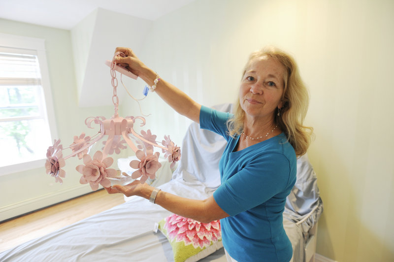 Designer Georgie McGowan shows off a vintage 1950s-era chandelier about to be hung in a young girl’s room.