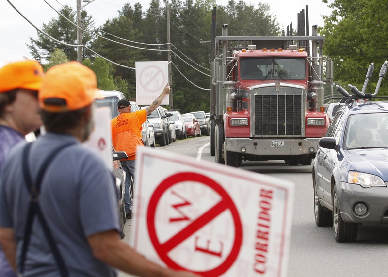 Protesters hold signs up prior to a public meeting in Dover-Foxcroft concerning the proposed east-west highway in May. The legislative sponsor of a study of the road says he underestimated opposition in his district.