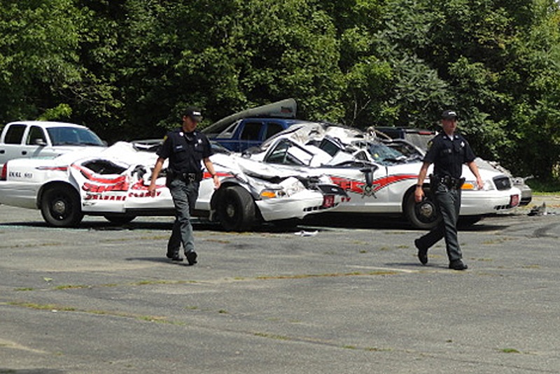 Sheriff officers walk past crushed cruisers at the Orleans County Sheriff's Department in Newport, Vt., Thursday, Aug. 2, 2012. Authorities say 34-year old Vermont farmer Roger Pion, angry over a recent arrest last month on charges of resisting arrest and marijuana possession, used a large tractor like a monster truck, destroying seven police cruisers. (AP Photo/Northland Journal, Scott Wheeler)