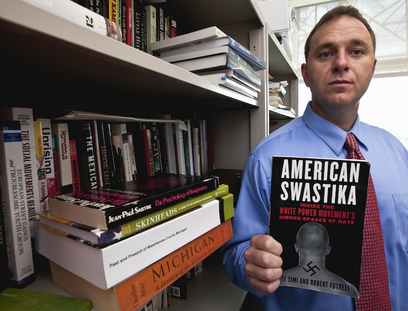 Pete Simi holds his book "American Swastika" while posing for a photo in his office in Omaha, Neb., Tuesday, Aug. 7, 2012. Simi, a professor at the School of Criminology and Criminal Justice at the University of Nebraska-Omaha, has done extensive field research into domestic hate groups, white supremacists and neo-Nazis. He knew Wade Michael Page, the Wisconsin Sikh temple gunman, from field research he did in southern California in 2001-2003 but had since lost touch with him. (AP Photo/Nati Harnik)