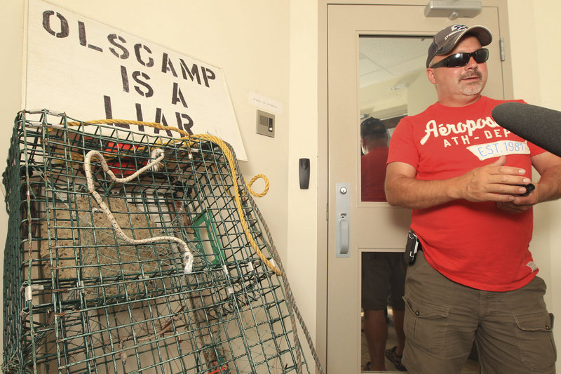 Protests in the Canadian Maritimes continued to escalate as more than 200 lobstermen converged on the offices of federal fisheries minister Keith Ashfield in Fredericton, New Brunswick, on Wednesday. Above, lobsterman Albert Hebert of Saint-Louis-de-Kent awaits access to the offices while, below, protesters attach signs to the entrance of the building. A meeting with Ashfield is scheduled Friday.