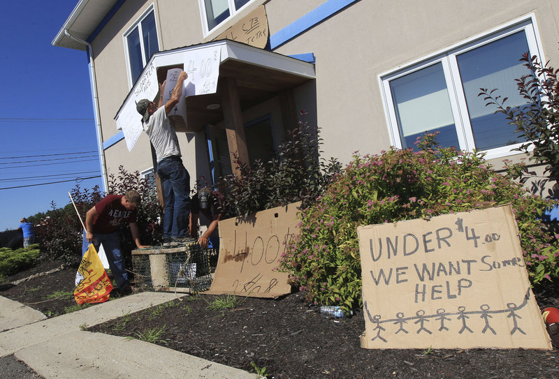 Protesters put up signs Wednesday outside the office of fisheries minister Keith Ashfield in Fredericton, New Brunswick. They are trying to get him to address the importing of cheap Maine lobster that makes it hard for Canadian lobstermen to compete and earn a profit.