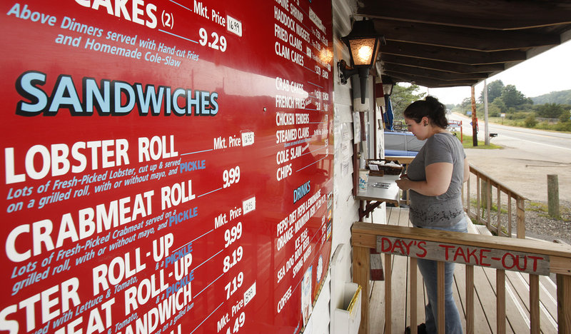 Nikki Salvia orders a crab roll Thursday at Day’s Take Out on Route 1 in Yarmouth, where the market price for a lobster roll was $12.95. Salvia is visiting Maine from New York.