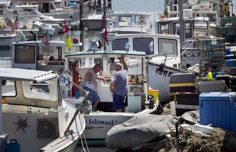 Robert F. Bukaty/The Associated Press Maine lobstermen take a break while doing maintenance work in Portland on Thursday. More than half of all lobsters caught in Maine goes to Canada for processing, but in a meeting Friday state officials began talking about increasing processing capacity in Maine.