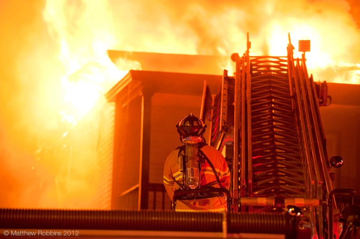 A firefighter helps battle the blaze Wednesday at 554 Main St. in South Portland.