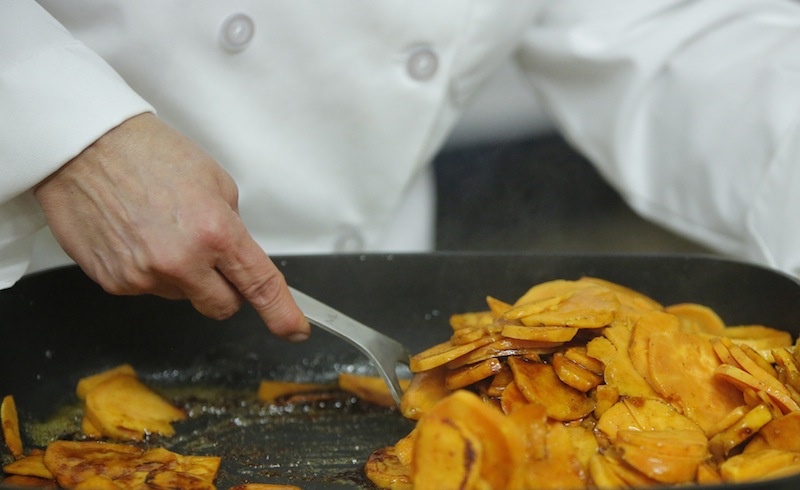 Ellen Demmons, food services director for RSU 21, stirs sweet potatoes while competing in a Iron Chef-type competition with Jonathan Cartwright, executive chef at the White Barn Inn, at Sea Road School in Kennebunk on Friday, September 28, 2012. The secret ingredient announced at the start of the competition was sweet potatoes and the school's fourth graders from the school were the judges of the chefs' final creations.