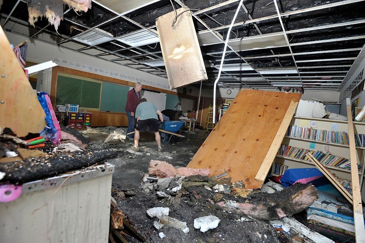 Volunteers, restoration workers and school personnel clean up one of the classrooms damaged by the fire at Hall School on Monday. Firefighters have determined that the fire originated in wiring to an exterior light.
