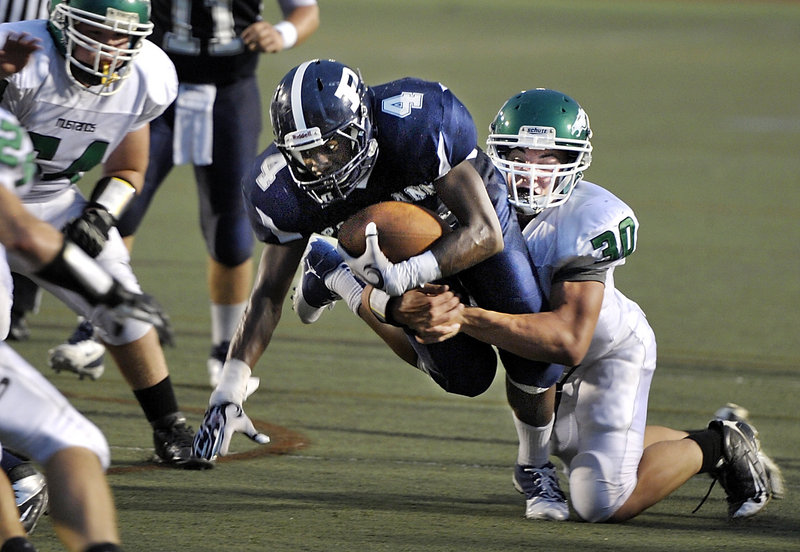 Jayvon Pitts-Young of Portland strives for the goal line but is stopped by Mike Risti of Massabesic during Portland’s 45-14 victory Friday night.