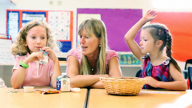 First-grade teacher Christine Hewey talks with Kate Cross, left, while Zola Bloom waits to ask a question at the start of class during the first day of school at East End School in Portland on Thursday, Sept. 6, 2012.