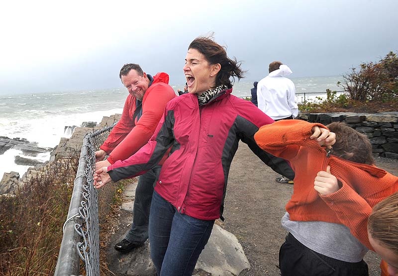 Michael and Kristin Guibord from Portland grab a fence and their two boys Orion 8 and Jonah 6 as they brace against the wind to view Portland Head Light in Cape Elizabeth on Mon. Oct. 29, 2012.
