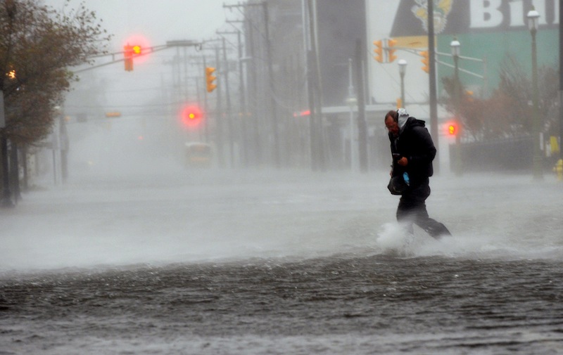Michael Wirtz, of Wilmington, Del., braves flood waters and high winds that arrive with Hurricane Sandy along North Michigan Avenue in Atlantic City, N.J., on Monday. Hurricane Sandy continued on its path Monday, forcing the shutdown of mass transit, schools and financial markets, sending coastal residents fleeing for higher ground, and threatening a dangerous mix of high winds and soaking rain.