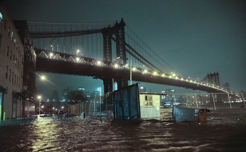 Streets are flooded under the Manhattan Bridge in the Dumbo section of Brooklyn, N.Y., Monday, Oct. 29, 2012. Sandy continued on its path Monday, as the storm forced the shutdown of mass transit, schools and financial markets, sending coastal residents fleeing, and threatening a dangerous mix of high winds and soaking rain. (AP Photo/Bebeto Matthews)