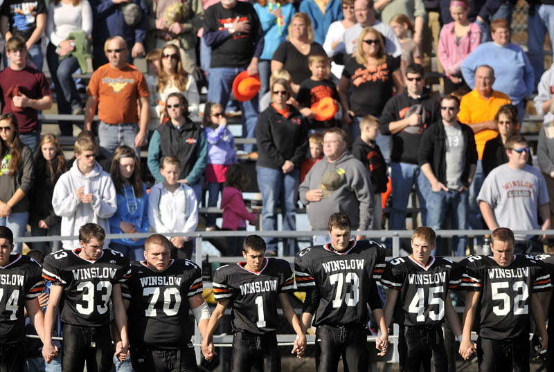 The Winslow High School football team holds hands during a moment of silence for two classmates killed in a car accident late Friday night.