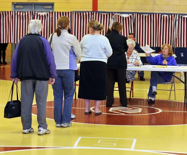 Gordon Chibroski / Staff Photographer. Tuesday, November 8, 2011. Hana Strnad, right, election clerk at the Boys and Girls Club voting place in South Portland hands a ballot to the person at the head of the line while fellow election clerk, Linden Sthigpen, left, verifies the voter's right to vote where the warden reported a healthy turnout.