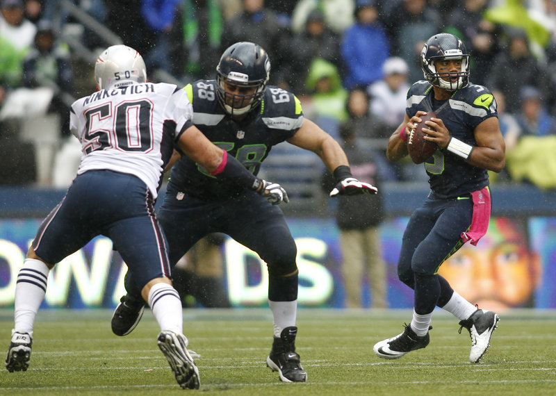 Seahawks quarterback Russell Wilson gets pass protection from teammate Doug Baldwin as he blocks the rush of New England’s Rob Ninkovich. Wilson stunned the Patriots with a 46-yard touchdown pass to Sidney Rice with 1:18 left in the game at Seattle on Sunday. The Seahawks scored 14 points in the final 7:31 to win it, 24-23.