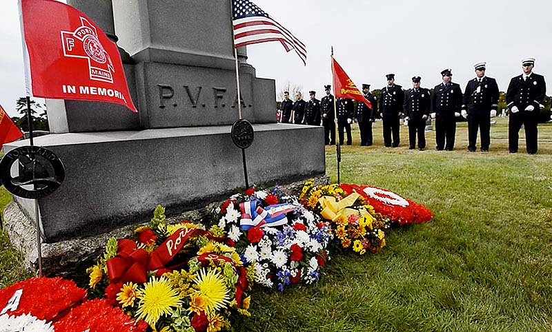 Firefighters stand near a monument to fallen firefighters at Forest City Cemetery in South Portland during the annual Memorial Sunday Service to honor firefighters who lost their lives in service.