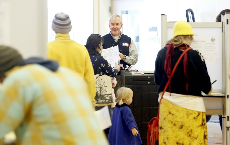 Volunteer election clerk Matt Fitzgerald collect ballots and hands out stickers to voters at the East End Elementary School in Portland on November 6, 2012. Tim Greenway/Staff Photographer