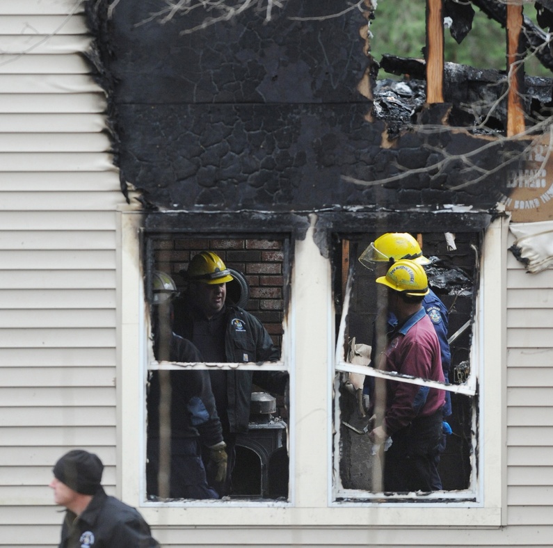 A team of state police and fire marshals confer inside the Orrington house where a man and his three children died in a fire Saturday.