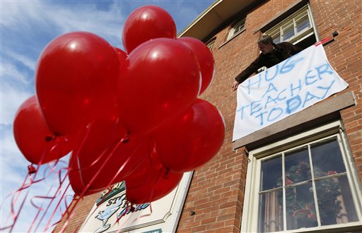 In this Dec. 15, 2012, photo, Gary Seri, general manager at the Stone River Grille, hangs a sign reading "HUG A TEACHER TODAY" written on a table cloth in honor of the teachers who died along with students a day earlier at the Sandy Hook Elementary School.