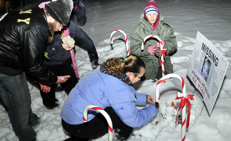 Vigil organizer Karen Francis and others place candles at the base of a poster with a photo of missing toddler Ayla Reynolds outside the girls home in Waterville on Monday, Dec. 17, 2012. Reynolds was reported missing one-year ago.