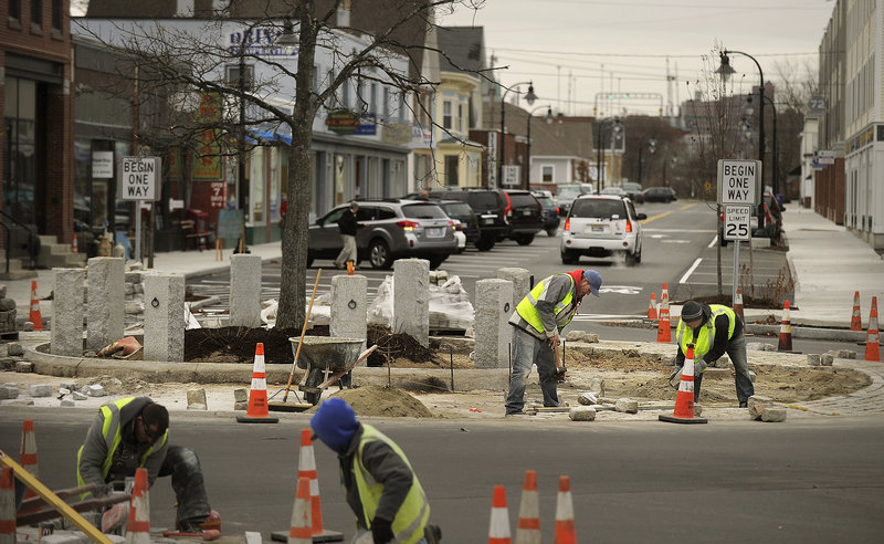 Workers from Maineway Landscaping and Excavation install bricks around the rotary in South Portland's Knightville last week.