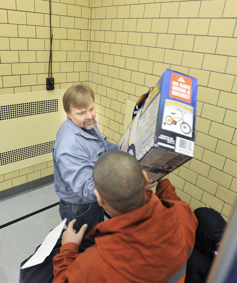 Gabe Souza/Staff Photographer: Gary Herson, a volunteer with the Salvation Army, hands a toy to a recipient at the Portland Corps of the Salvation Army on Cumberland Avenue Tuesday, December 18, 2012, as families began picking up their gifts for the holidays.