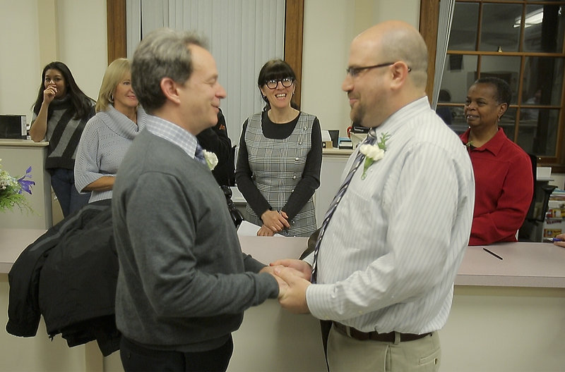 Christine Horne, center, a vital records clerk at Portland City Hall, marries Jeff Burdick, left, and Josh Laton at City Hall on Saturday.