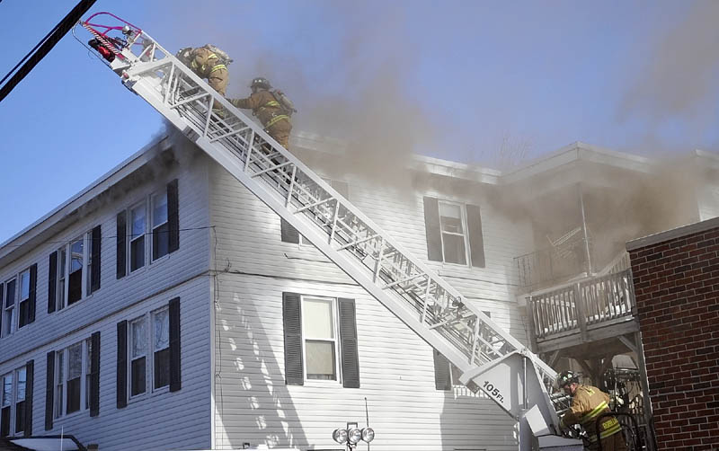 Augusta firefighters work on a ladder truck in front of an apartment building that burned Thursday on Sewall Street in Augusta.