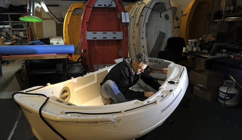 Portland Pudgy operations manager Daniel Mosher installs electrical components in one of the company’s boats recently at the Portland headquarters.