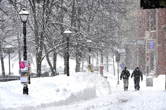 John Patriquin/Staff Photographer: Large snowflakes fell before a freezing rain as Portlanders make their way around the messy streets and sidewalks of intown Portland Monday Feb.11,2013 after a blizzard hit Maine this past weekend. This scene is in Monument Square toward Free st.