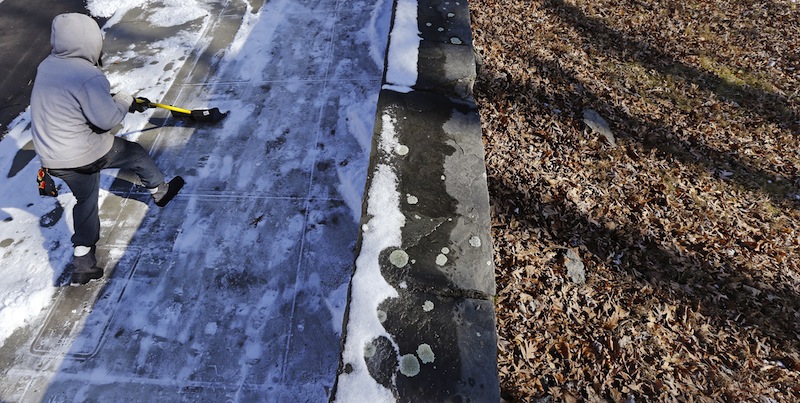 With the museum grounds covered with leaves and bare of snow, J Lajik shovels the snow-covered walkway outside the National Center of Afro-American Artists after overnight flurries in the Roxbury neighborhood of Boston, Wednesday, Feb. 6, 2013. A midwinter storm headed to the Northeast on Friday could drop more than a foot of snow. (AP Photo/Charles Krupa)