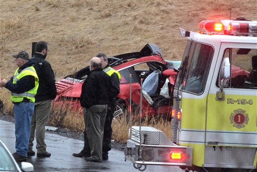 Emergency personnel stand near the wreckage of a sports car that was involved in a wreck with a tour bus carrying members of the St. Michael's College lacrosse team on Tuesday. A female passenger in the sports car was killed in the crash.