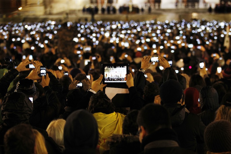 Visitors take photos of Pope Francis as he speaks from the central balcony of St. Peter's Basilica at the Vatican, Wednesday, March 13, 2013. Cardinal Jorge Bergoglio, who chose the name of Francis is the 266th pontiff of the Roman Catholic Church. (AP Photo/Michael Sohn)