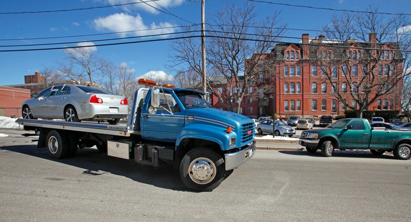 A flatbed tow truck pulls away Tuesday morning from Parish Place Apartments in Biddeford with a silver Chevy Malibu with Massachusetts plates. Residents say it was the car in which a man's body was found this morning.