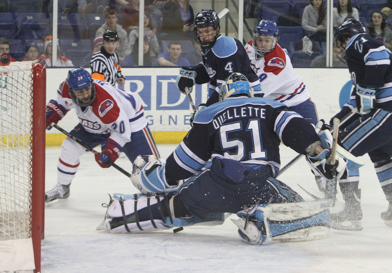 UMass-Lowell’s Michael Fallon slides the puck under Maine goalie Martin Ouellette but wide of the net while Jake Rutt (4) and Kyle Beattie (21) defend.