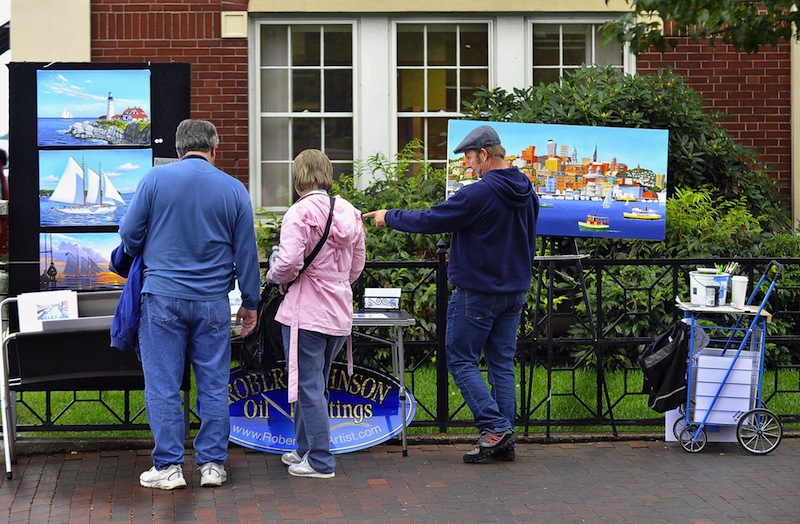 In this October 2011 file photo, artist Robert Johnson answers questions from patrons on a corner of Commercial Street near DiMillo's. City councilors may move Tuesday, April 8, 2013 to further restrict where street art vendors can set up their tables on city sidewalks.