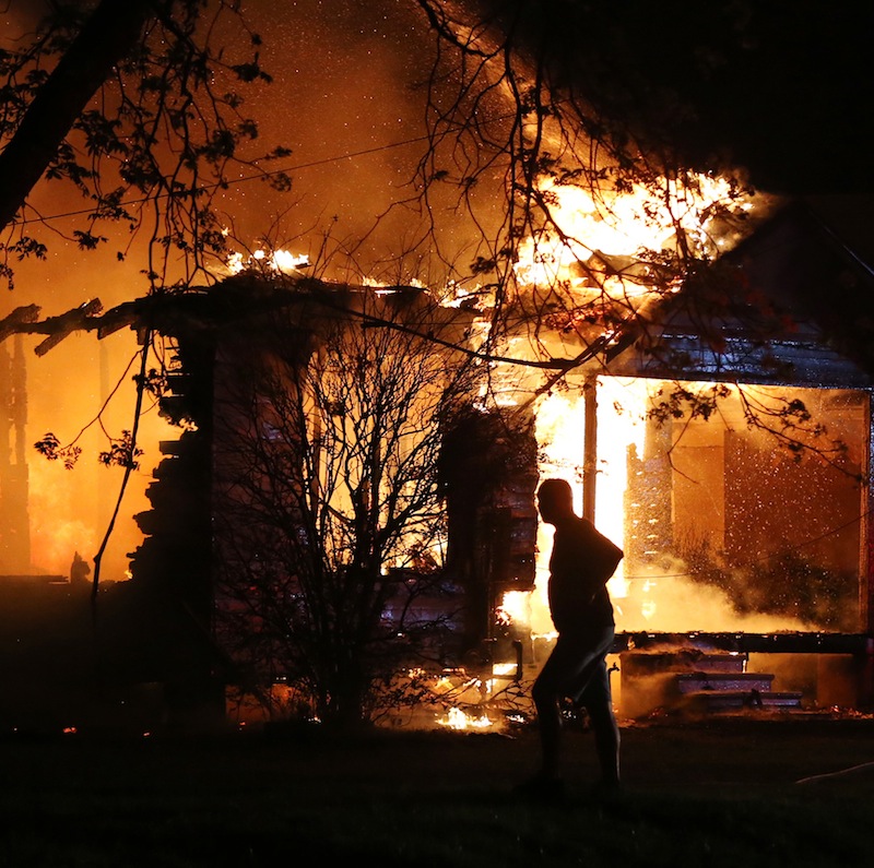 A person looks on as emergency workers fight a house fire after a nearby fertilizer plant exploded Wednesday, April 17, 2013, in West, Texas. A massive explosion at the fertilizer plant near Waco on Wednesday night injured dozens of people and sent flames shooting into the night sky, leaving the factory a smoldering ruin following a blast that damaged buildings for blocks in every direction. (AP Photo/Waco Tribune Herald, Rod Aydelotte)